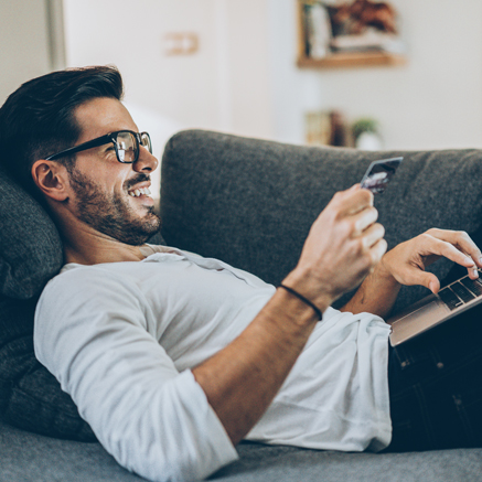 Instead do this... Man laying on couch with laptop and debit card typing